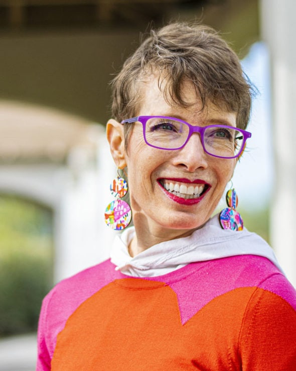 Jodie, wearing a bright sweater and pink glasses.