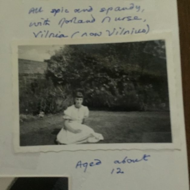 A black and white photo of a girl sitting on a grassy area.