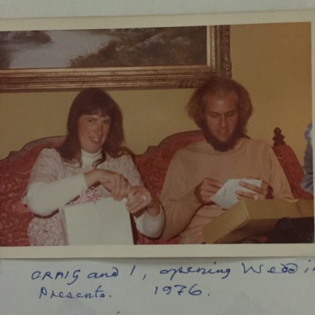 A newly married couple in the 1970s, sitting on a couch.