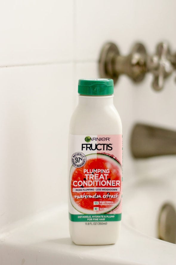 Garnier watermelon plumping conditioner, on the edge of a tub.