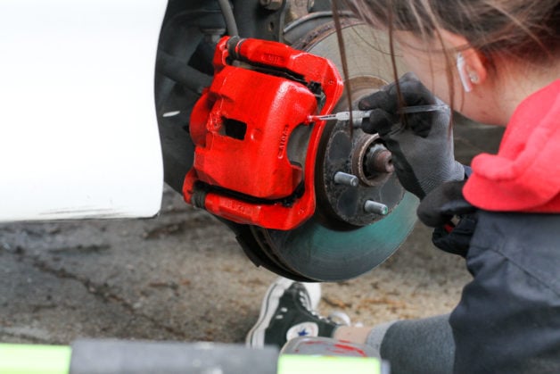 Red calipers being painted by hand.