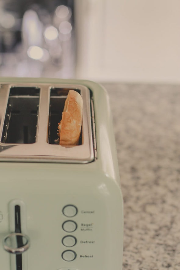 A bagel in a light green toaster.