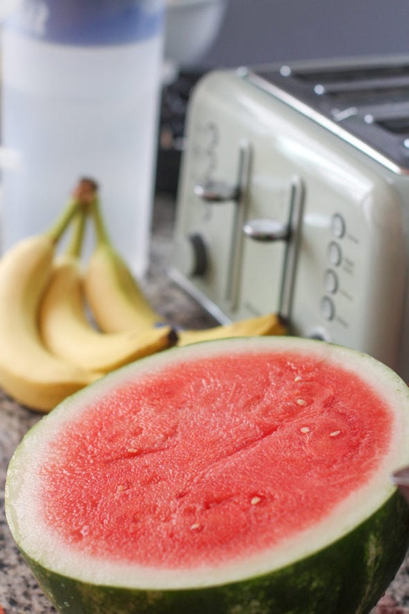 Half of a red watermelon, sitting on a counterop.