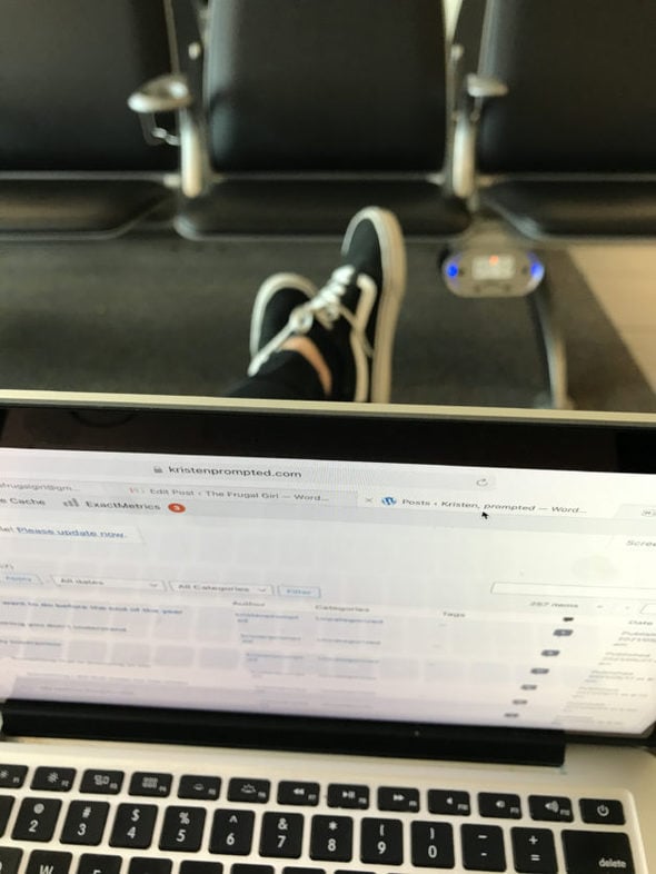 A laptop half open, with a pair of shoes in the background.