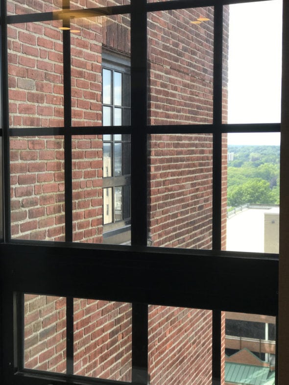 A view of a brick wall through a black-framed window.