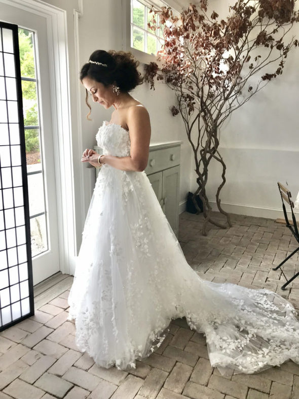 A bride with dark hair, looking down at her hand.