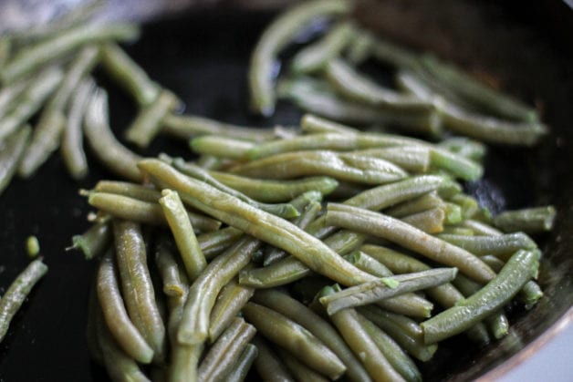 Frozen green beans in a skillet.