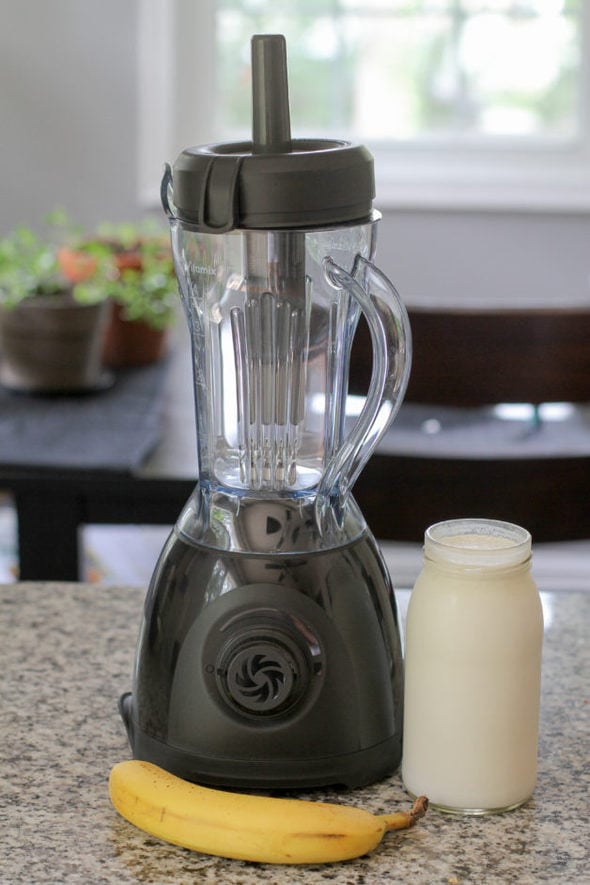 A Vitamix One blender with a banana and a glass jar of yogurt.