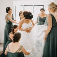 A group of bridesmaids helping a bride adjust her dress.