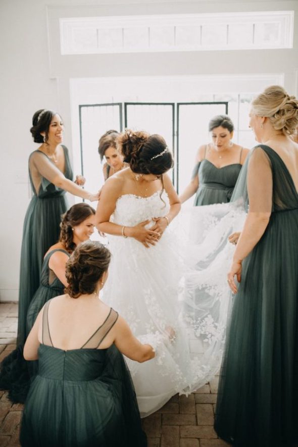 A group of bridesmaids helping a bride adjust her dress.