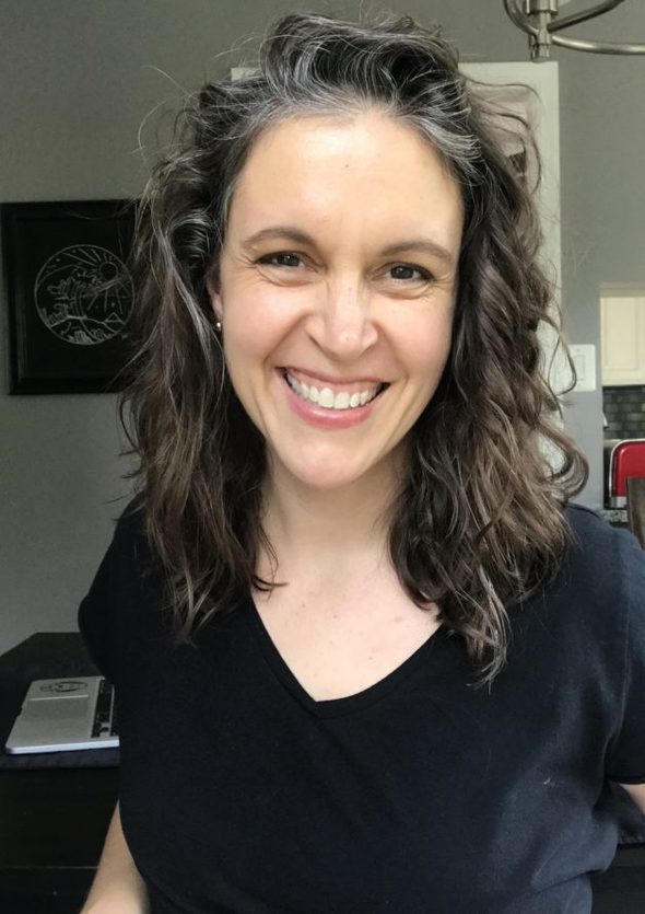 Kristen in a black shirt with wavy hair, smiling.