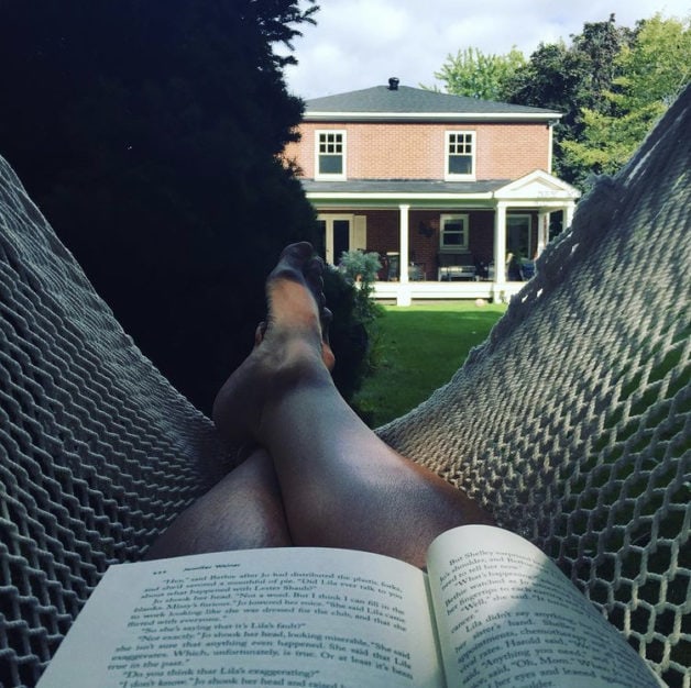 A view from a hammock with a book in a person's lap.