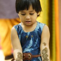 A little Indian girl looking at her arms.