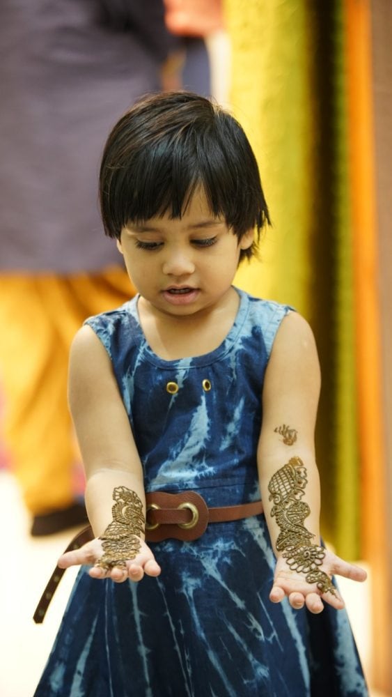 A little Indian girl looking at her arms.