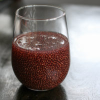 Red chia drink in a glass on a wood table.