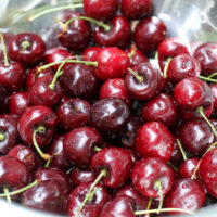 Cherries in a metal strainer.