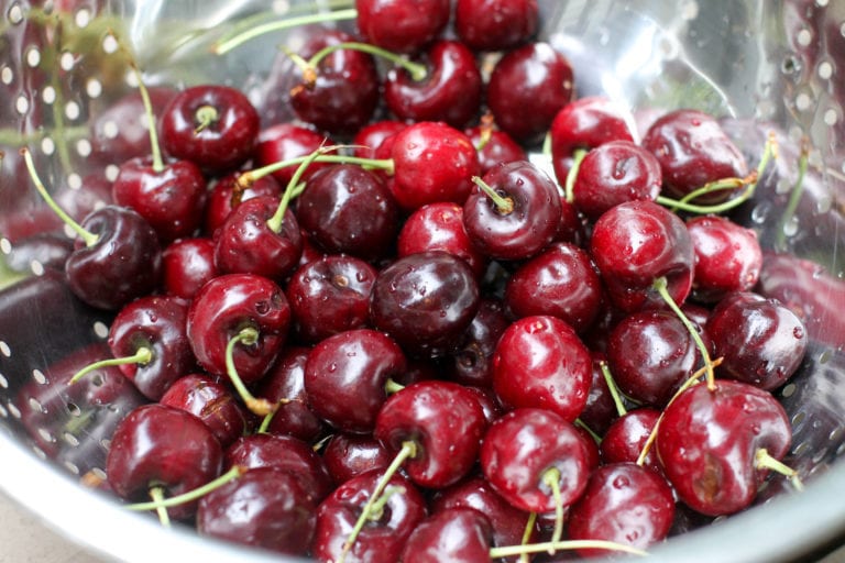 Cherries in a metal strainer.
