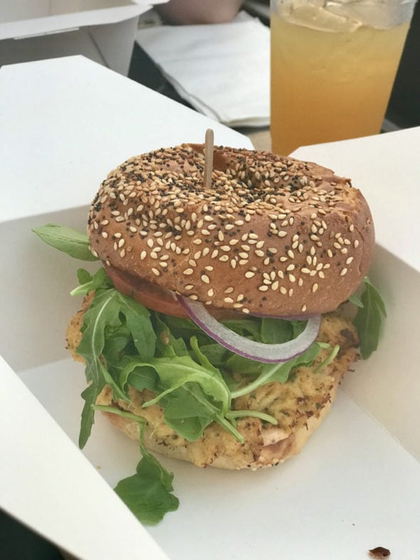 Crab cake sandwich with arugula and red onion.