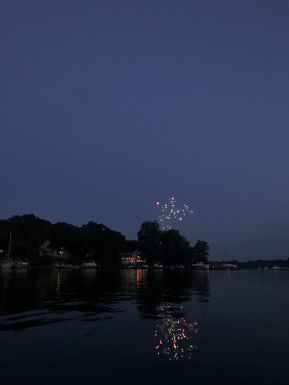 Fireworks in the sky over a river.