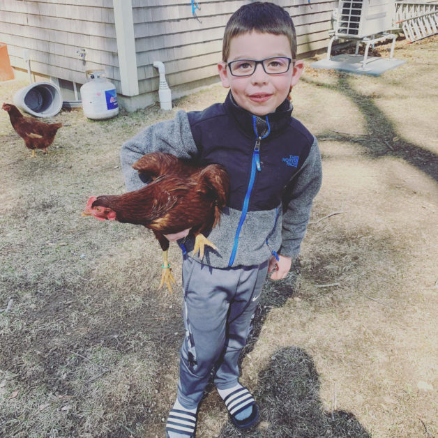 A boy holding a chicken.