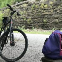 A bike in front of a railroad embankment.