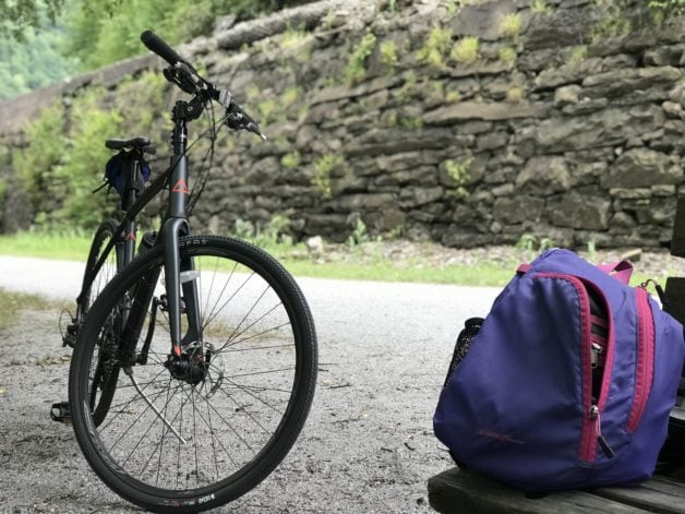 A bike in front of a railroad embankment.