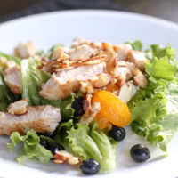 A green salad with chicken and fruit.