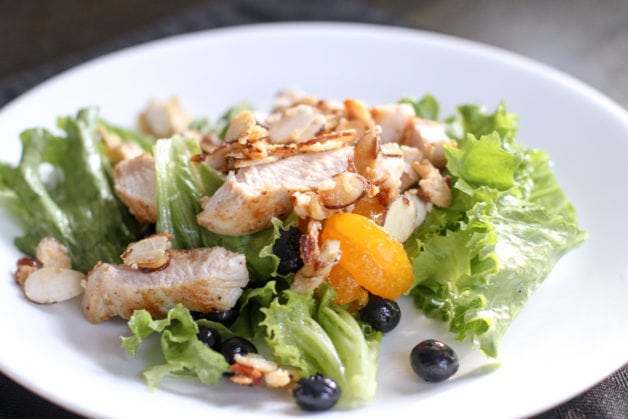 A green salad with chicken and fruit.