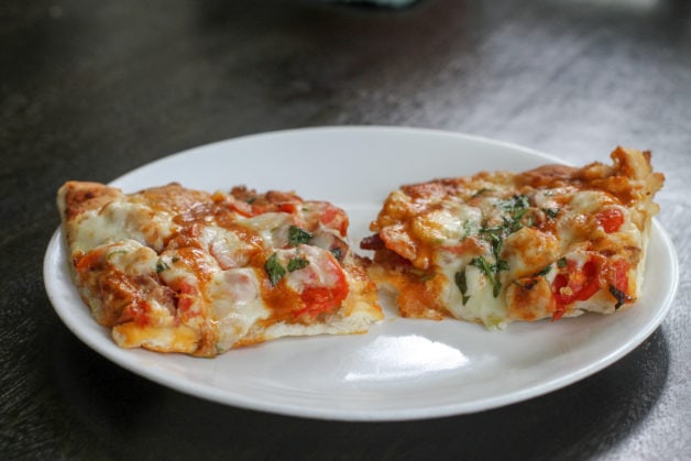 two pieces of Panera flatbread pizza on a white plate.