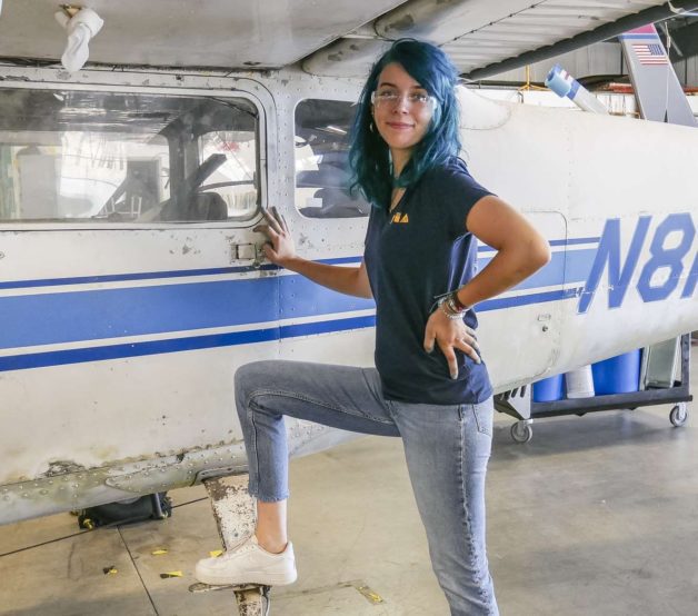 Lisey standing next to a small airplane.