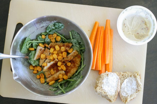 A spinach salad in a metal bowl.