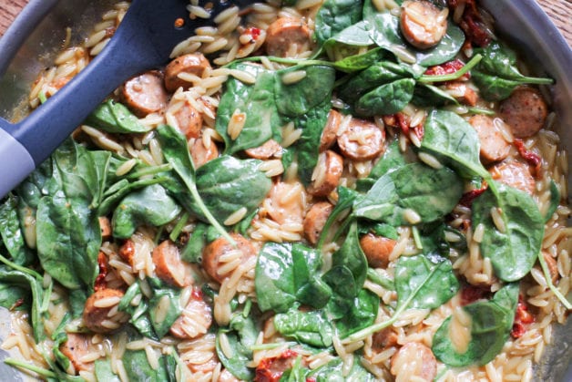 Orzo and spinach in a pan.