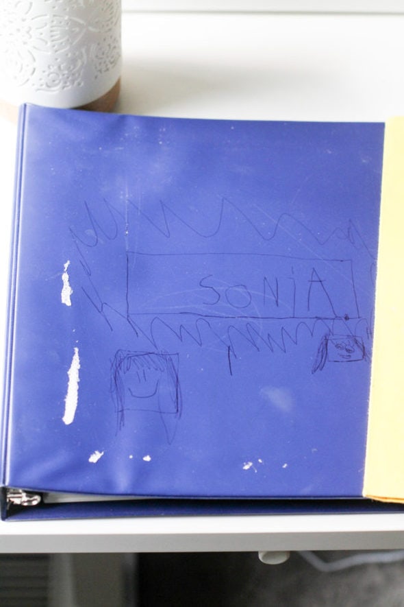 A blue binder decorated with kid drawings.