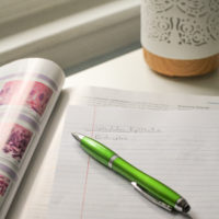 A green pen on a lined notebook page.