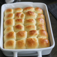 Potato rolls in a white oblong pan.
