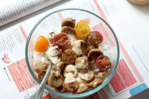 A bowl of rice, sausage, and veggies.