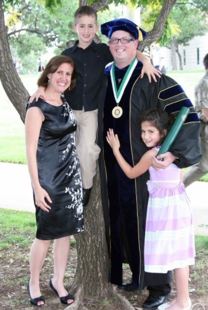 Rachel and family with her husband in graduation garb.