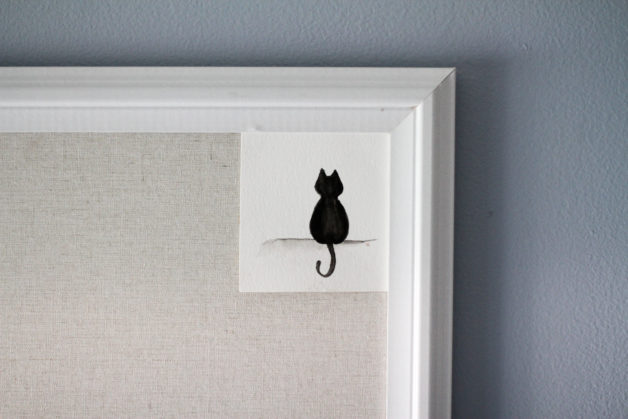 A black cat watercolor painting on a bulletin board.