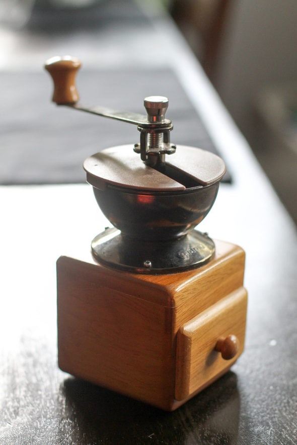 A manual coffee grinder with a wooden drawer.