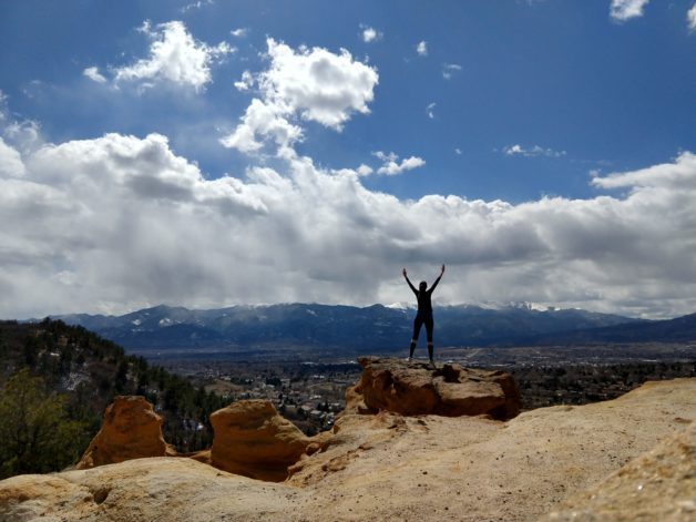 A silhouette of a person on a rock lookout.