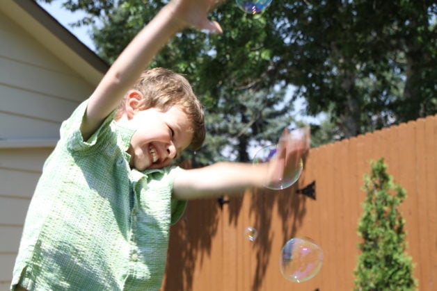 A little boy blowing bubbles.