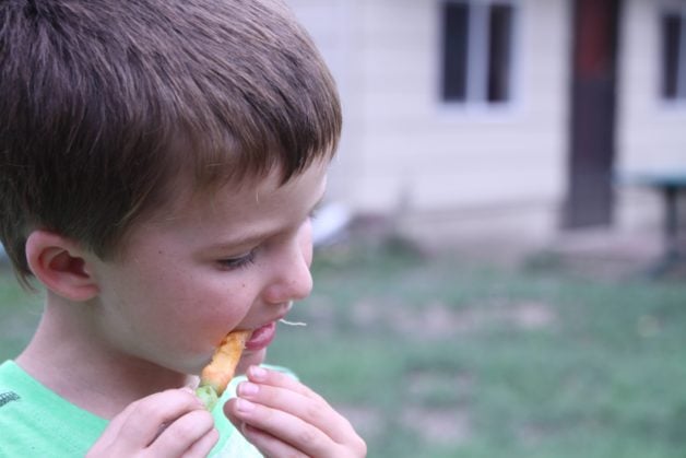 A boy eating a carrot.
