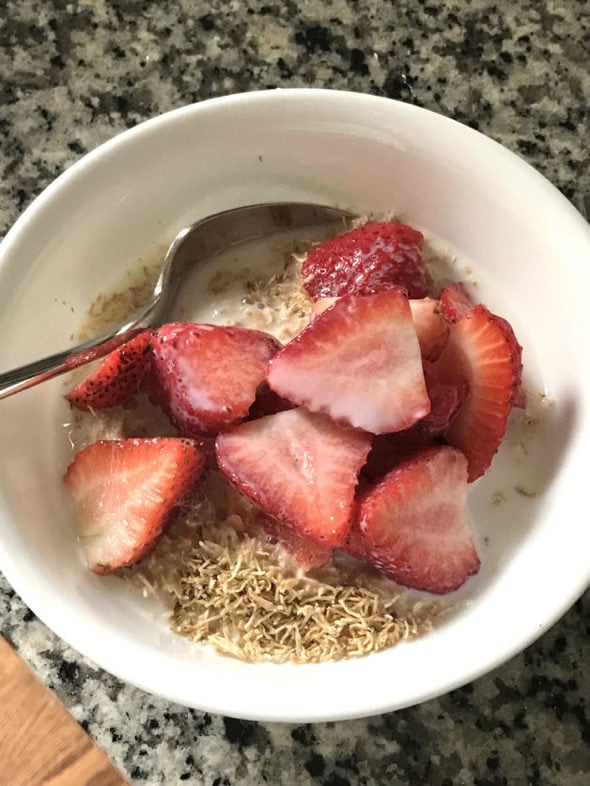 A bowl of shredded wheat topped with strawberries.