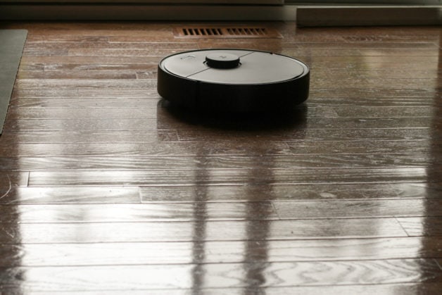 A black robot vacuum on a wood floor.