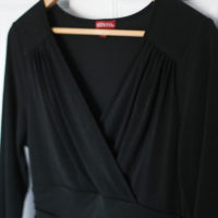 A black dress on a wooden hanger.