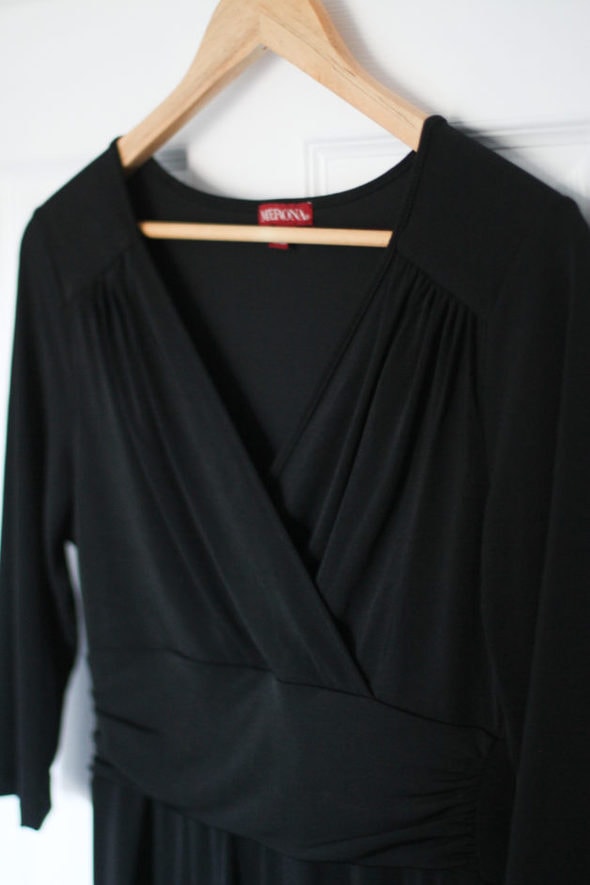 A black dress on a wooden hanger.