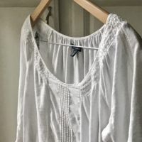 a laundered white shirt on a wooden hanger.
