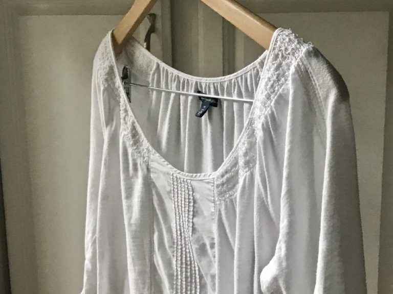 a laundered white shirt on a wooden hanger.