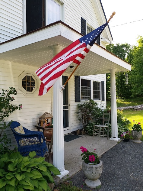 A white home with a flag flying on the porch.