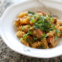 rotini and kielbasa topped with parsley, in a white bowl.